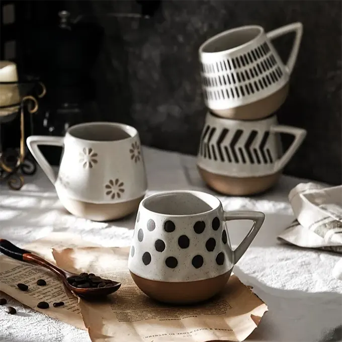 4 Tasses blanches avec des motifs géométriques posées sur une table avec des déc